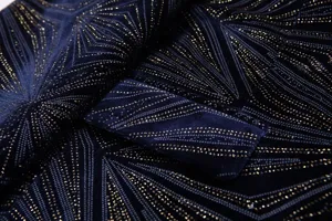 Vista detallada de tela de traje de terciopelo azul oscuro con patrón geométrico dorado.