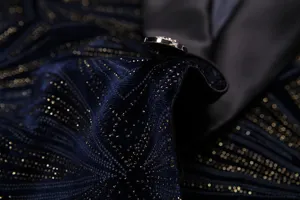 Vista detallada de tela de terciopelo azul oscuro con patrón dorado brillante y botón.