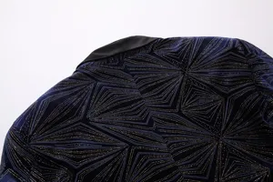 Primer plano de detalle de un blazer de terciopelo azul oscuro con motivo geométrico dorado.