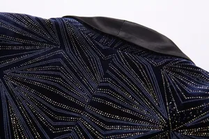 Primer plano detalle de blazer de terciopelo azul oscuro con motivo geométrico dorado.