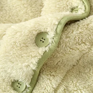Primo piano del tessuto in pile spesso e caldo per cardigan con bordo verde e bottoni coordinati.