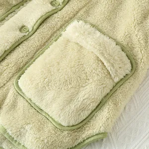 Primo piano sul dettaglio del cardigan in morbido pile, abbigliamento caldo da casa.