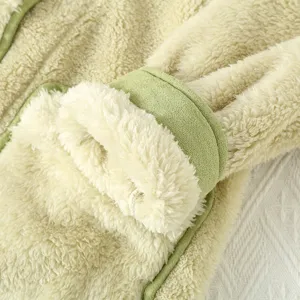 Dettaglio di spessa vestaglia in pile invernale panna con bordo verde tessuto caldo morbido