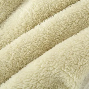 Primo piano del tessuto in pile sherpa beige, consistenza morbida e calda per pigiami accoglienti.