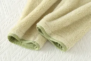 Primo piano dettagliato della manica del pigiama in morbido pile con bordo verde contrastante.