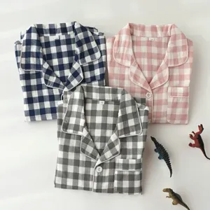 Vue détaillée du haut de pyjama à carreaux pour enfants avec revers et boutons en trois couleurs.