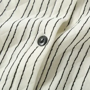 Close-upweergave van gestreepte air-cotton moederschap pyjama stoftextur en zwarte knop detail.