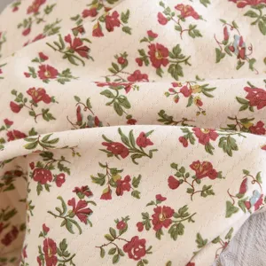 Vue détaillée du tissu matelassé avec imprimé floral rouge vintage, texture douce et confortable.
