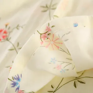 Detail view of cotton gauze fabric with floral print, soft texture and fine stitching for sleepwear.