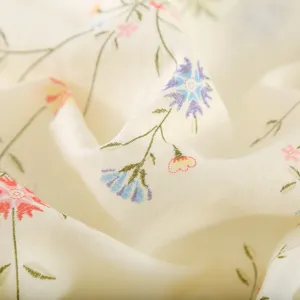 Detailed view of soft pale yellow cotton gauze fabric featuring a delicate floral print design.