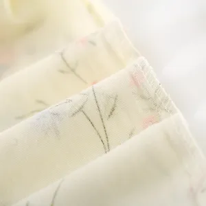 Close up view of soft cotton gauze fabric with delicate floral print and neat edge stitching.