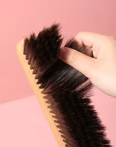 Close-up detail of soft bristle bed cleaning brush with wooden handle for dust removal.