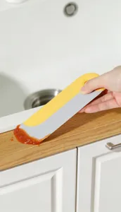 Japanese kitchen cleaning scraper tool detail showing grease and residue removal on kitchen counter.