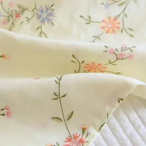 Close-up detail of light yellow floral cotton fabric, soft and breathable for sleepwear.