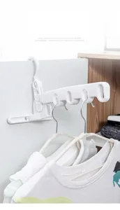 Foldable 5-hole clothes drying rack hanging on a white door panel with clothes detail