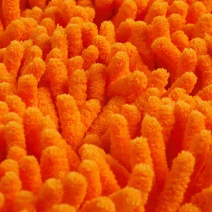 Close-up macro shot of soft orange chenille microfiber fabric texture with dense long piles.