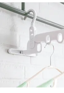 Close-up of a white plastic foldable 5-hole clothes drying rack hook on a rod