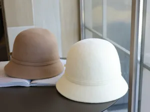 Detail view of elegant wool felt cloche bucket hats in beige and white with delicate bow trim.
