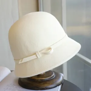 Detail view of the elegant cream wool cloche hat, featuring a delicate side bow and ribbon trim.