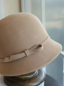 Close-up detail of elegant khaki wool felt cloche hat with delicate side bow design.