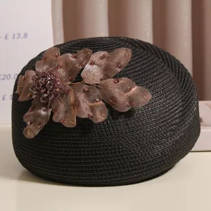Schwarze geflochtene Strohbaretthut mit eleganter brauner Stoffblume und funkelnden Strass.