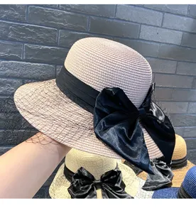 Close-up detail of women summer straw sun hat featuring elegant black bow and mesh veil.