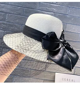 Close up view of the summer straw hat featuring black ribbon, elegant bow and mesh face veil.