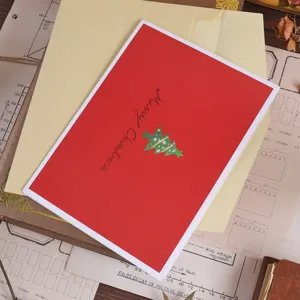 Detailed top view of a red 3D Christmas tree greeting card and envelope on vintage paper.