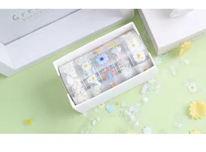 Detail view of transparent PET decorative tape rolls featuring cute daisy floral patterns for journaling.