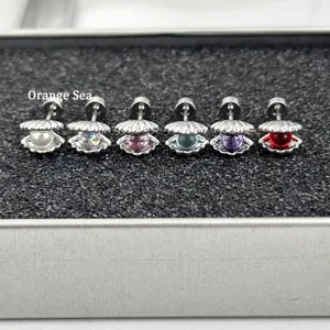 Close-up detail shot of stylish shell ear studs with colorful pearl balls arranged neatly.