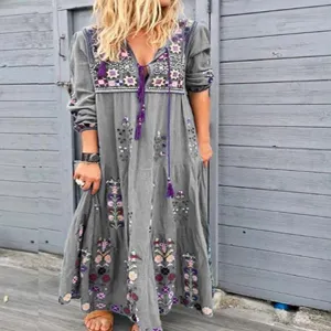 Detalle de vestido largo bohemio con bordado floral y borlas moradas