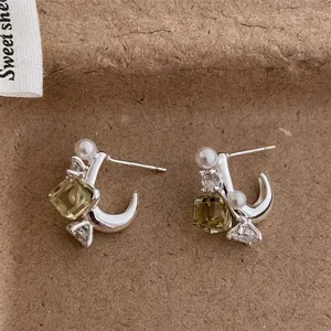 Detailed shot of silver geometric crystal pearl earrings with unique square yellow stone design.