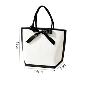 Sac-cadeau en papier blanc avec nœud ruban noir, emballage de shopping élégant.