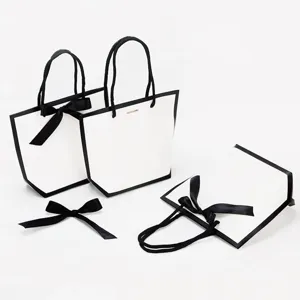Sacs cadeaux en papier blanc minimaliste avec bords noirs et nœuds rubans pour le shopping