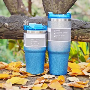 Blue glitter stainless steel vacuum insulated coffee tumblers displayed on autumn leaves