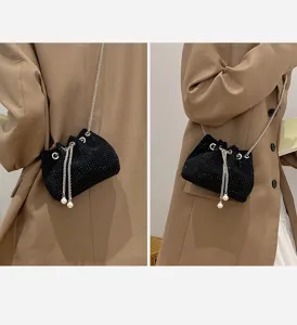 Detailed view of black rhinestone drawstring evening bag with chain strap and pearls.