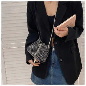 Elegant rhinestone bucket bag with drawstring and pearl detail, worn with a black blazer.