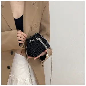 Elegant black rhinestone drawstring bucket bag with metal chain strap worn by a model