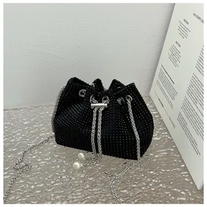 Detailed view of a black rhinestone bucket bag with silver chain and pearl drawstrings