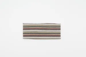 Nahaufnahme des gestreiften breiten Strickstirnbands im Retro-Stil mit warmen Herbstfarben.