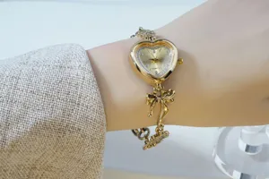 Vintage gold heart bracelet watch featuring rhinestone dial and sweet bow detail close view.