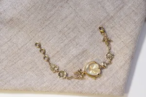 Detailed view of vintage gold heart-shaped bracelet watch with bow and flower charms.