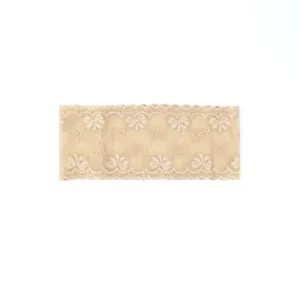 Close-up detail of beige lace stretch headband featuring delicate floral bow pattern.