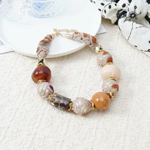 Close-up detail of Bohemian style fabric-wrapped beaded necklace with chic Maillard color.