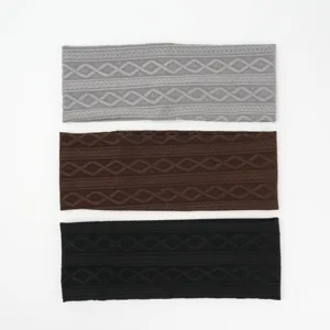 Detailed shot of three knitted headbands in grey, brown, and black with classic pattern.
