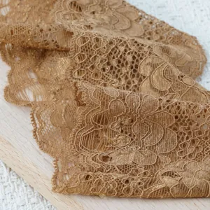 Detaillierte Nahaufnahme der goldenen elastischen Spitzenborte mit feinem Blumenmuster.