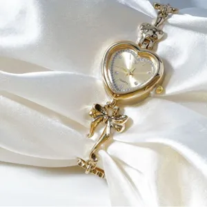 Women's gold heart-shaped quartz watch with elegant bow bracelet strap, fashion timepiece.