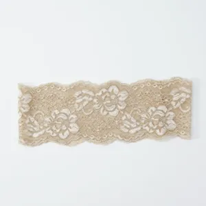 Nahaufnahme von beiger elastischer Spitzenborte mit filigranem Blumenmuster für Heimwerken.