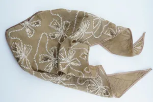 Primer plano detalle del pañuelo de cabeza champagne bordado con lentejuelas y motivo floral.