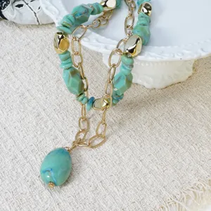 Detalle del elegante collar de piedra multicapa con cuentas turquesas y cadenas doradas.